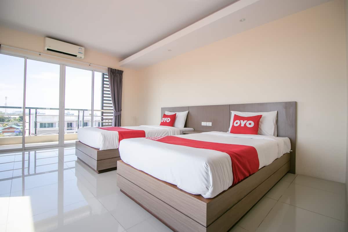 A modern hotel room with two beds, large windows, and a balcony.
