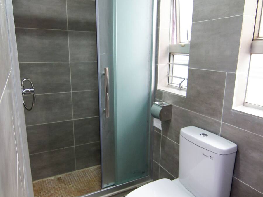 A bathroom with a toilet, a glass-enclosed shower, and a window.