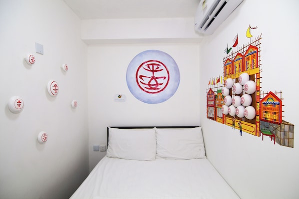 A hotel room with a bed, a wall with a circular symbol, and a mural of buildings.
