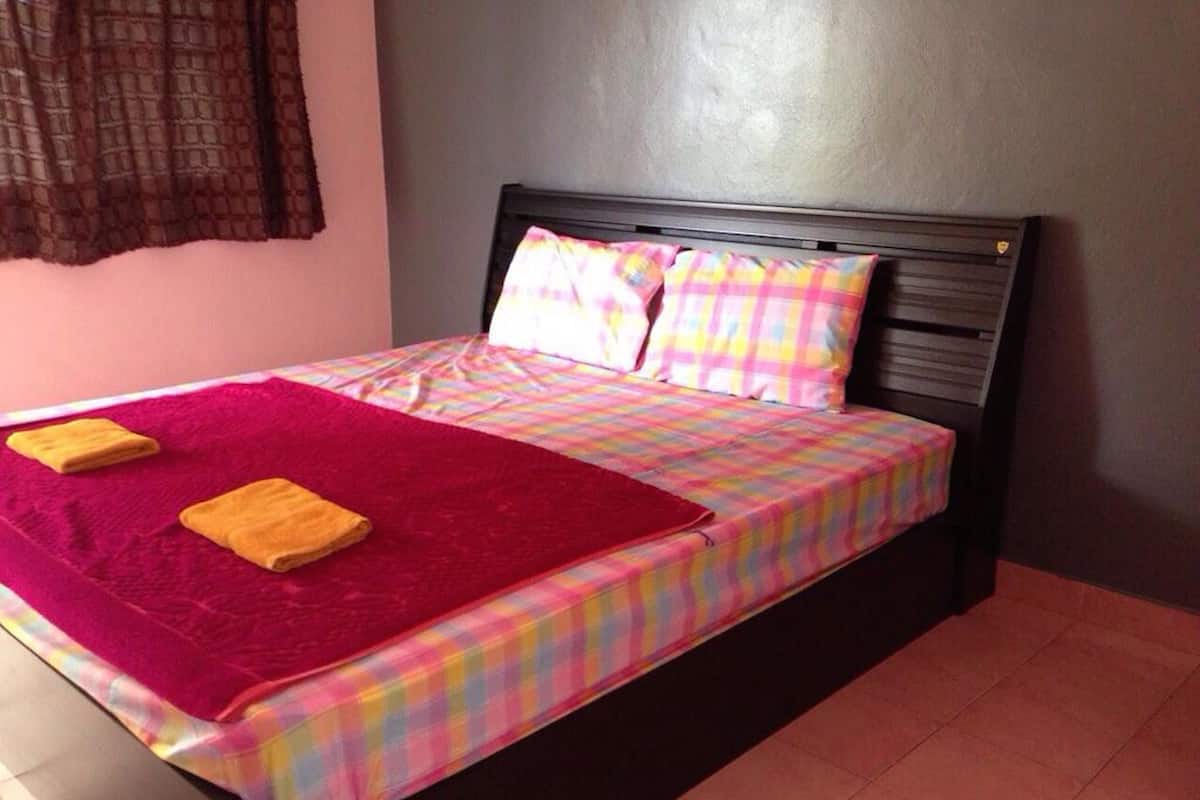 A bed with a colorful plaid bedspread, two pillows, and two yellow towels.