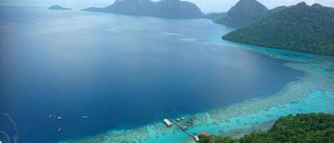 An aerial view of a coastal area with clear blue waters, small islands, and a dock with boats.
