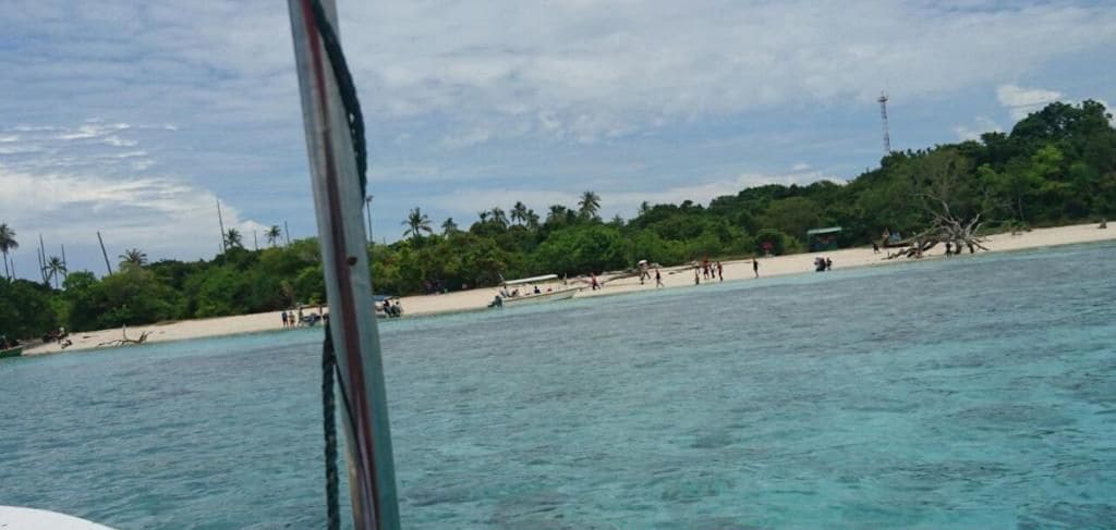 A boat near a beach with clear turquoise water and a sandy shore.