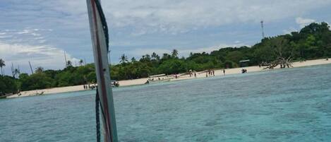 Un bote cerca de una playa con agua turquesa cristalina y una orilla arenosa.