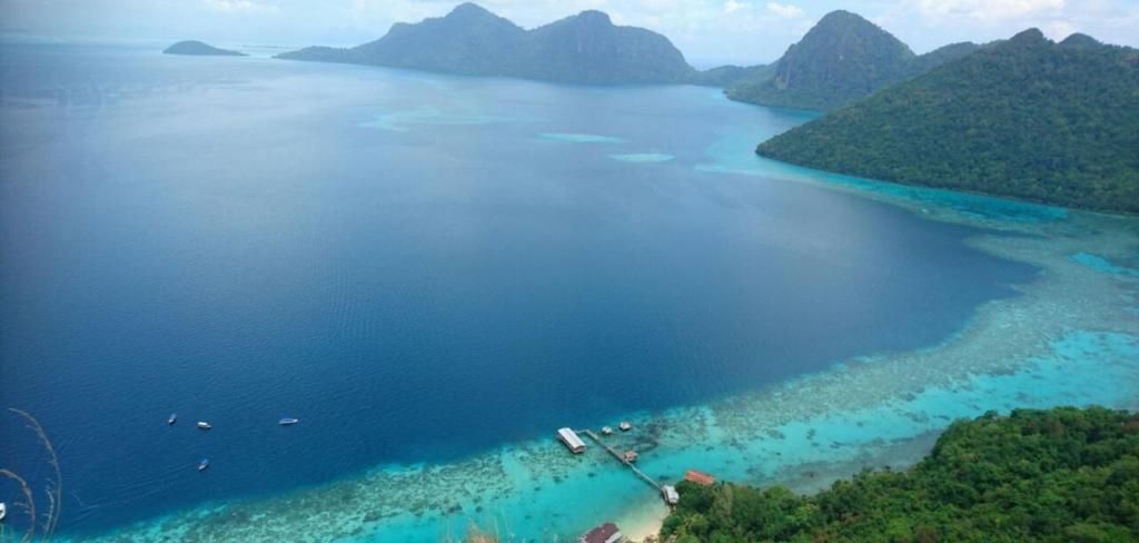 A coastal view of Bohey Dulang Island with clear turquoise waters and a dock.
