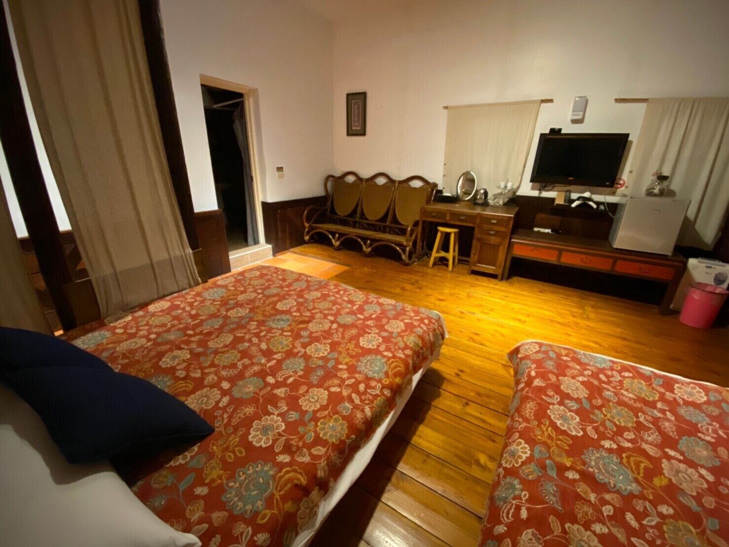 A hotel room with two beds, a desk, a chair, a television, and a small table.