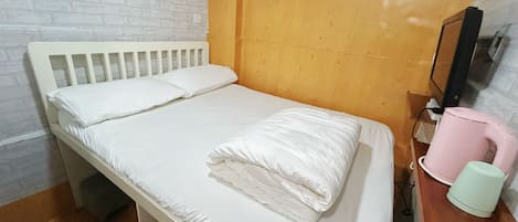 A single bed with white bedding, a wooden headboard, and an air conditioning unit mounted on the wall above.
