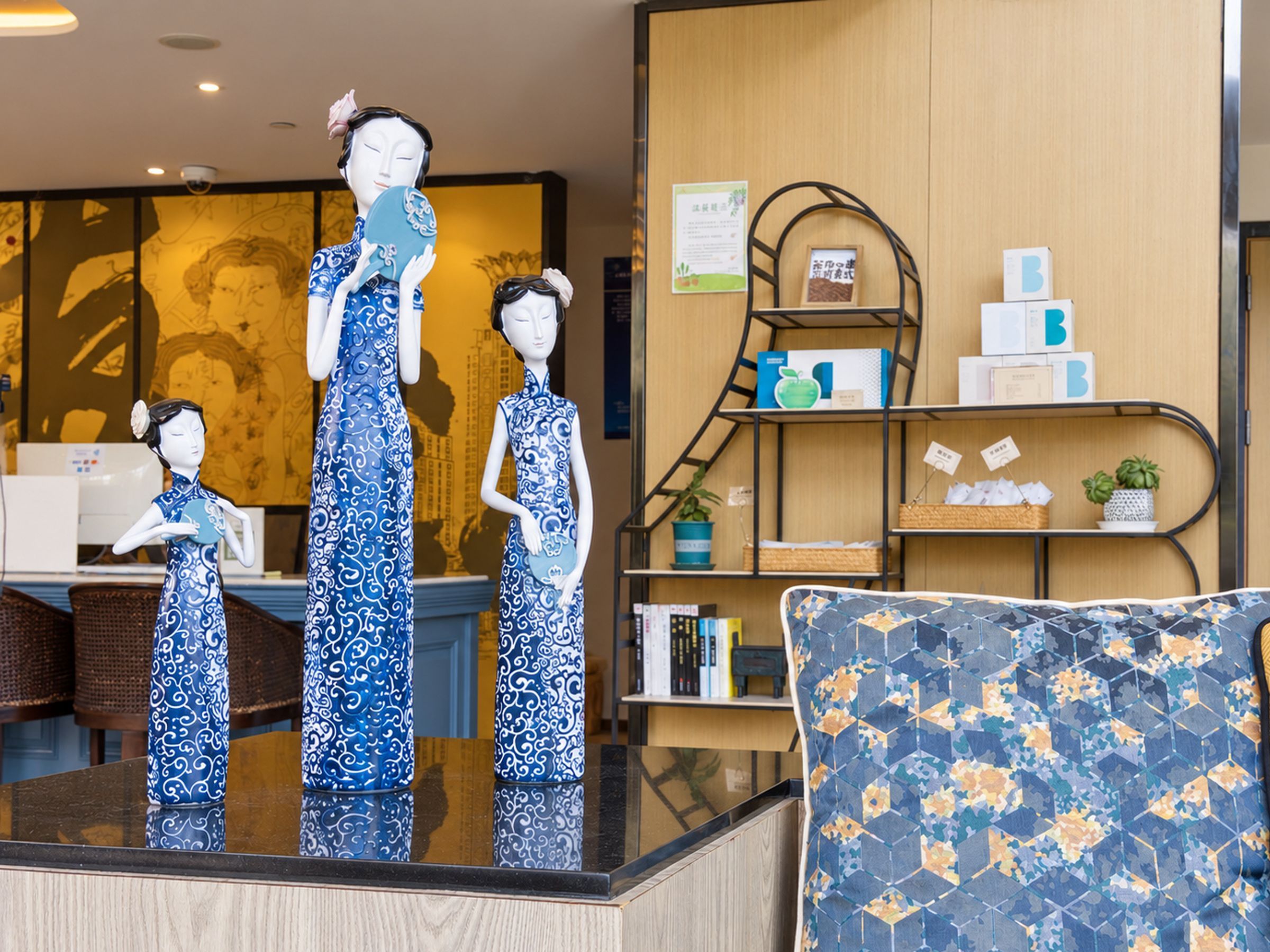 A room with a reception desk, a blue patterned sofa, and decorative items including figurines and a bookshelf.