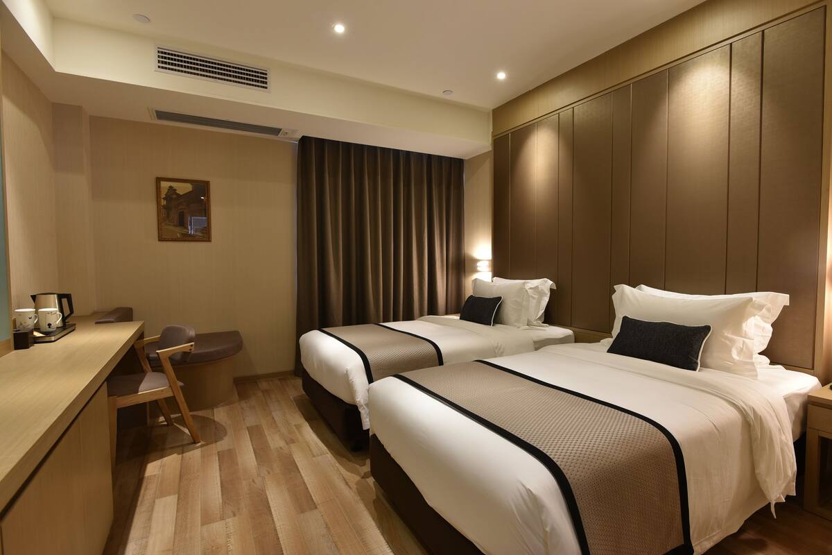 A hotel room with two beds, a desk, and a chair.