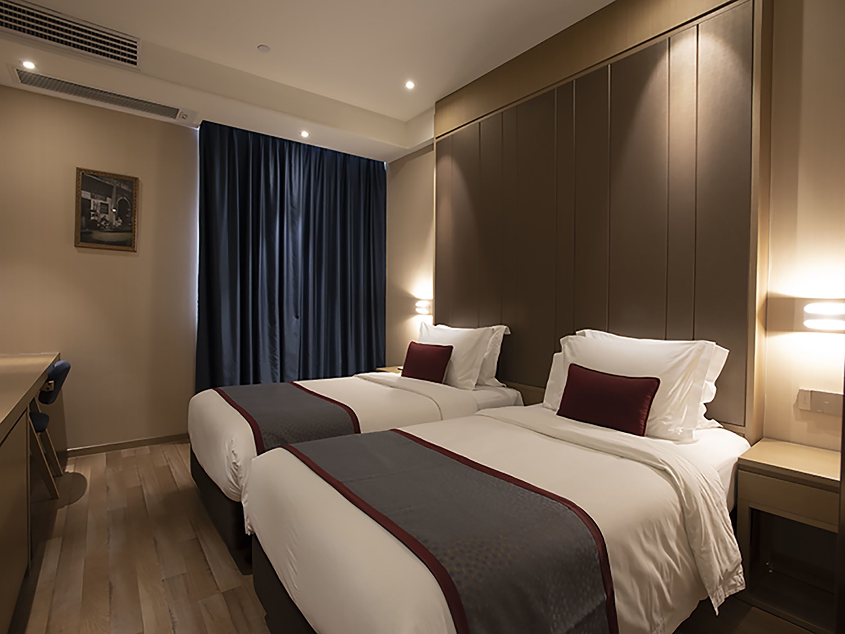 A hotel room with two beds, a desk, and a nightstand.