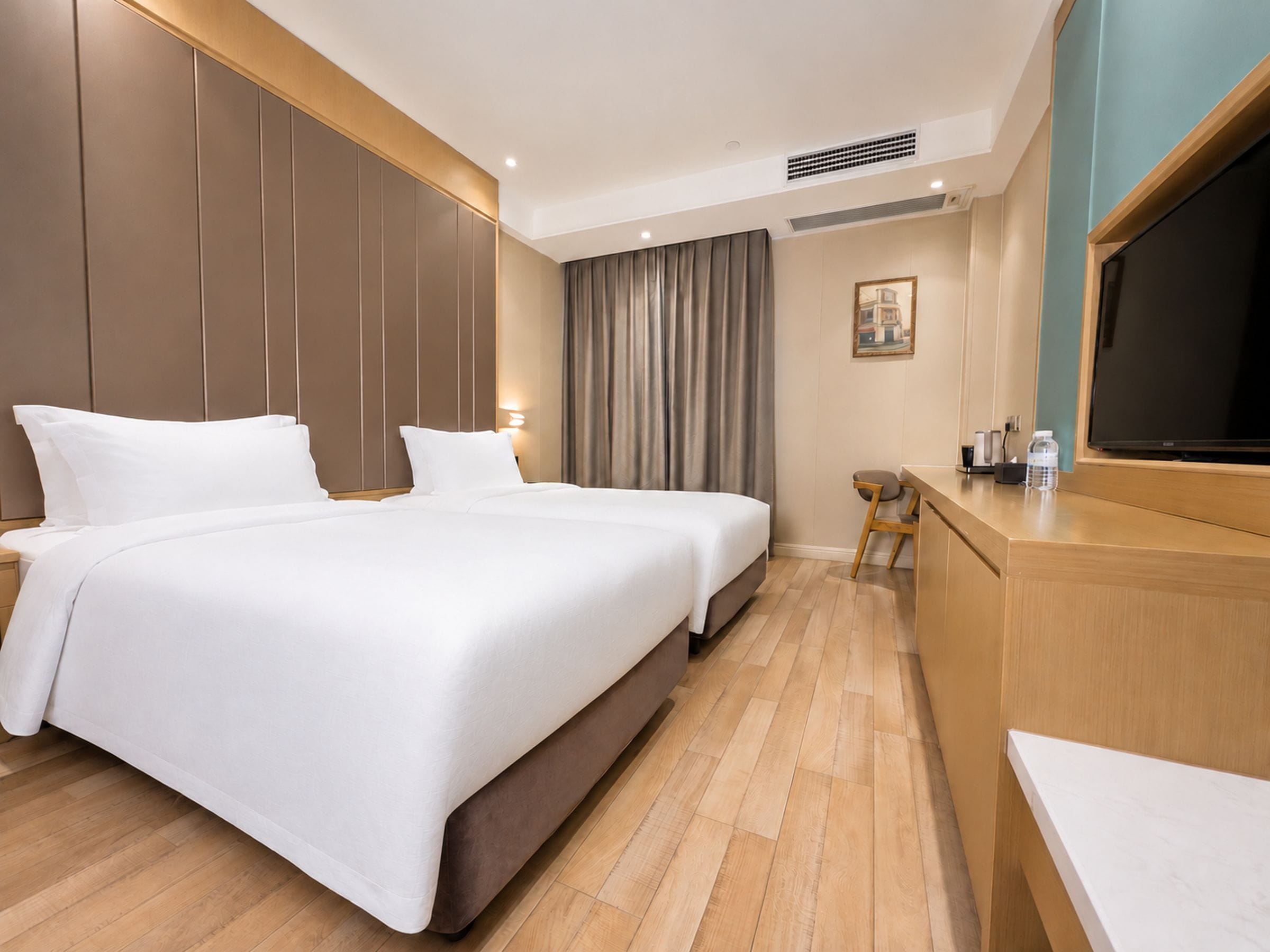 A hotel room with a large bed, a desk with a chair, a television, and a painting on the wall.