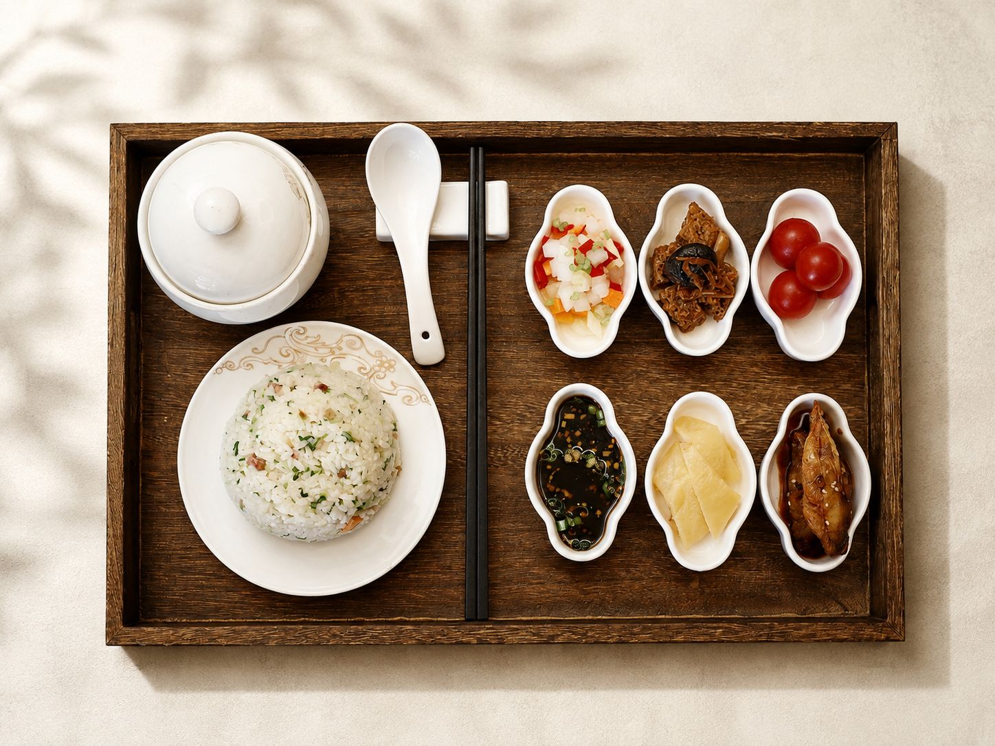 Una bandeja de madera con un tazón de arroz, una cuchara y varios pequeños platos con diferentes alimentos.