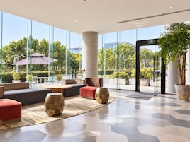 A modern lobby with large glass windows, seating areas, and a central column.