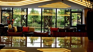 A modern living room with a reflective floor, large windows, and a sofa with cushions. - SHANGHAI-DECO Hotel (Shanghai)