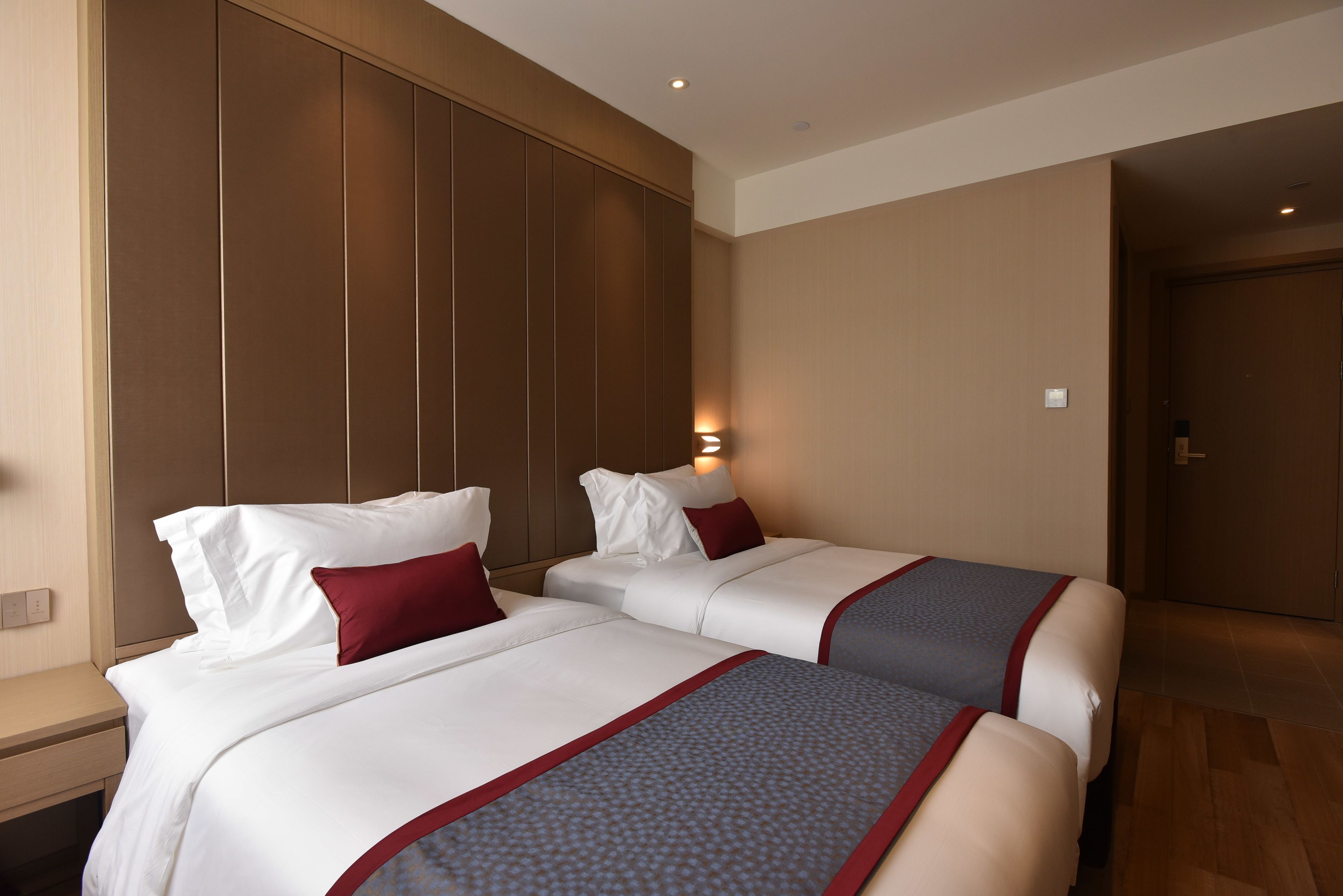 A hotel room with two beds, wooden paneling on the walls, and a nightstand.