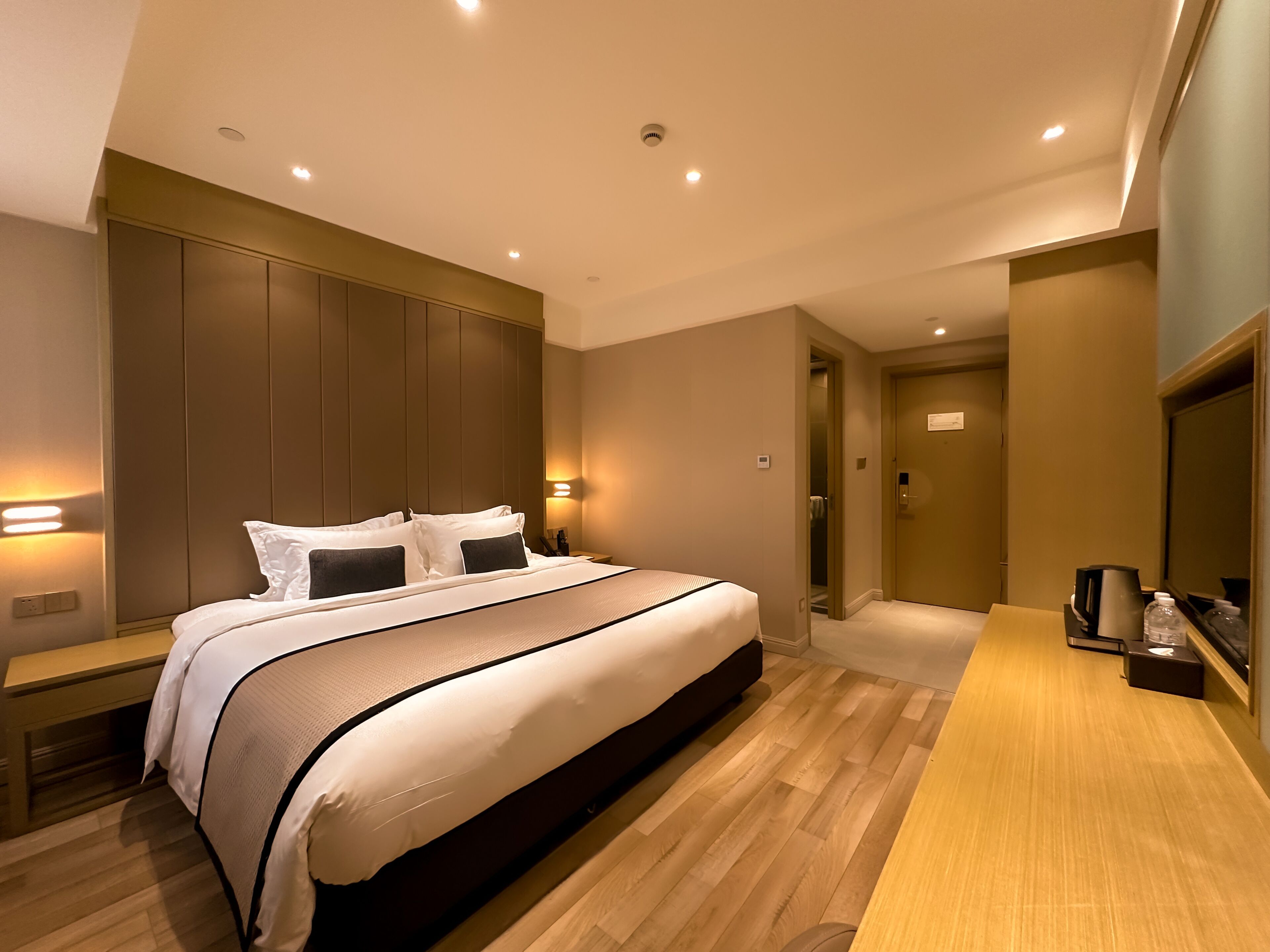 Ein modernes Hotelzimmer mit einem großen Bett, Holzboden und einem Einbauschrank.