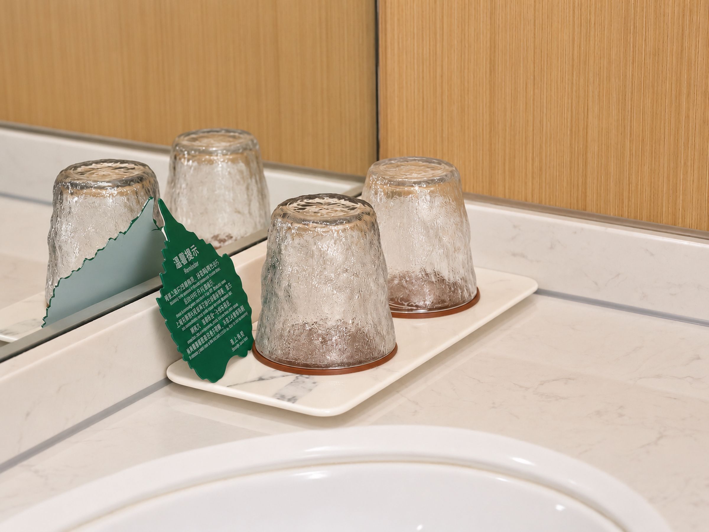 Een badkamer met een wit wastafelmeubel, een spiegel en een aanrecht met vier glazen.'