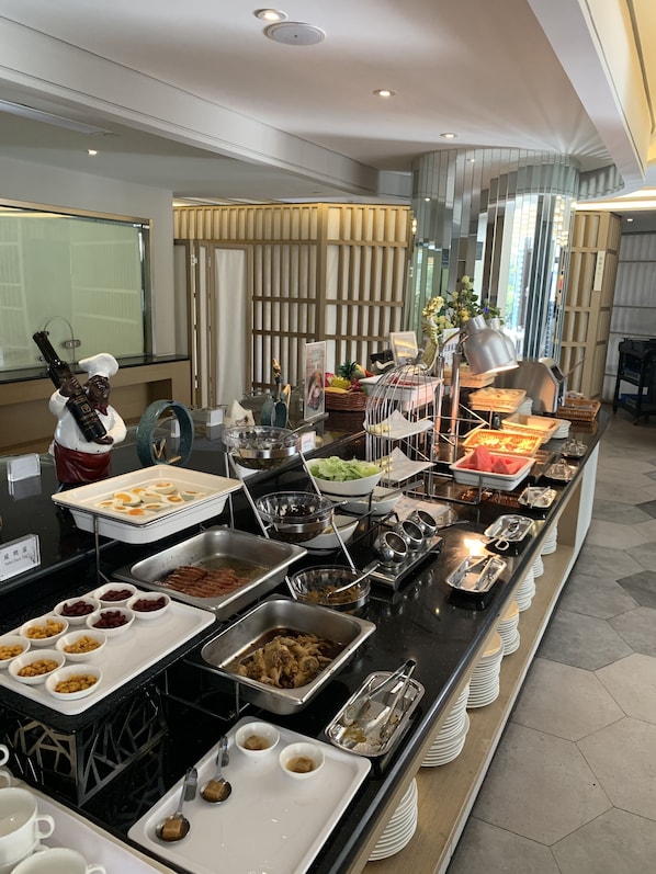 Mesa de buffet com diversos alimentos e utensílios.