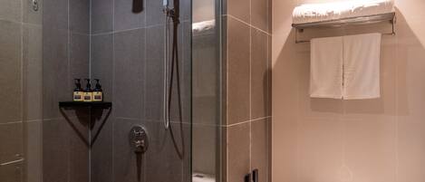 A modern bathroom with a glass-enclosed shower, a toilet, and a towel rack.