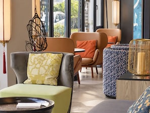 Un hall d’hôtel moderne, aménagé avec des espaces salon, une table basse et une lampe décorative.