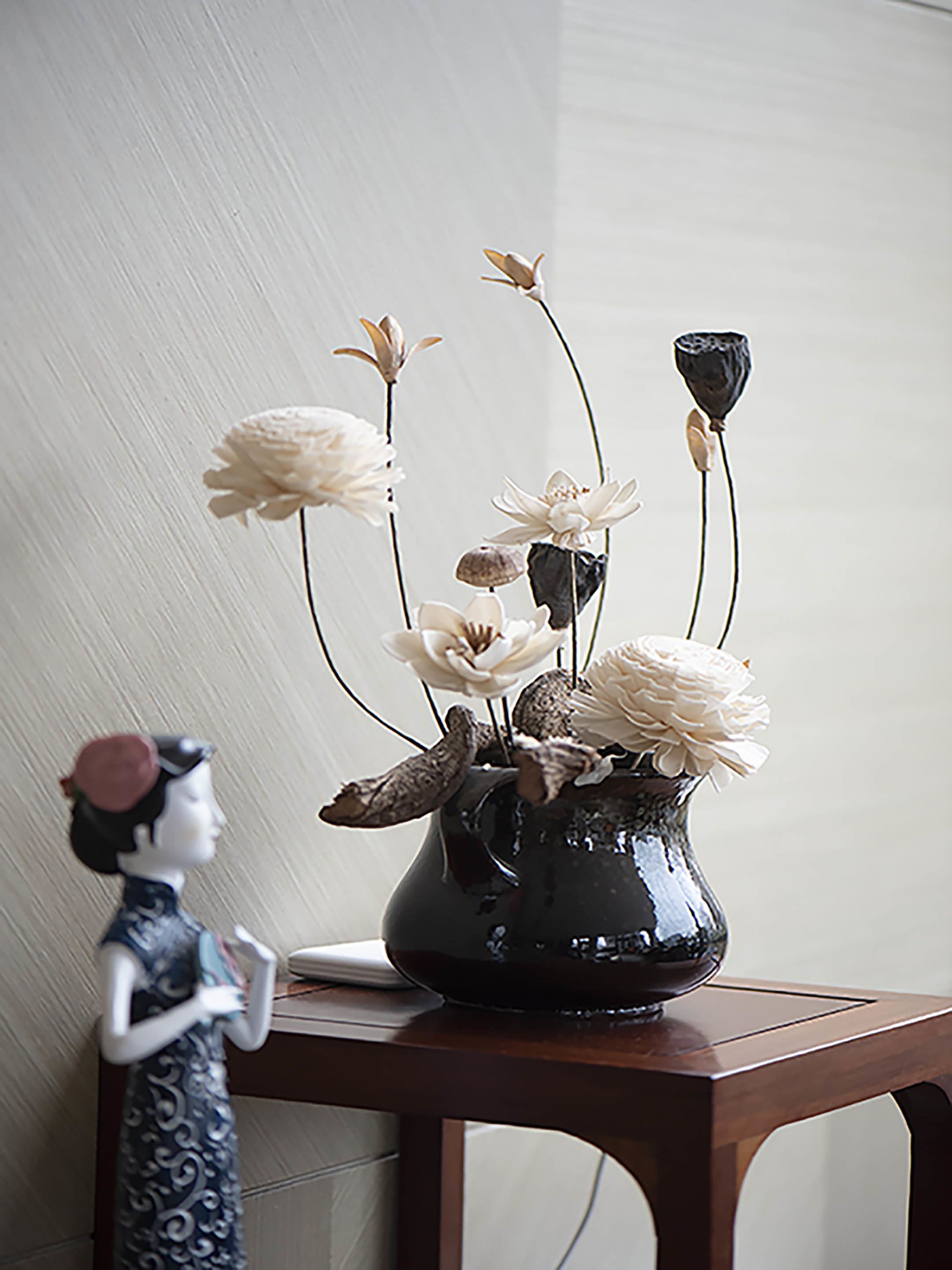 A vase with flowers on a wooden table against a plain wall.