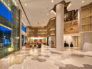 Eine geräumige Lobby mit hoher Decke, einem Empfangsschalter und einer großen Säule.