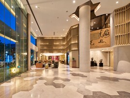 A spacious lobby with a high ceiling, a reception desk, and a large column.