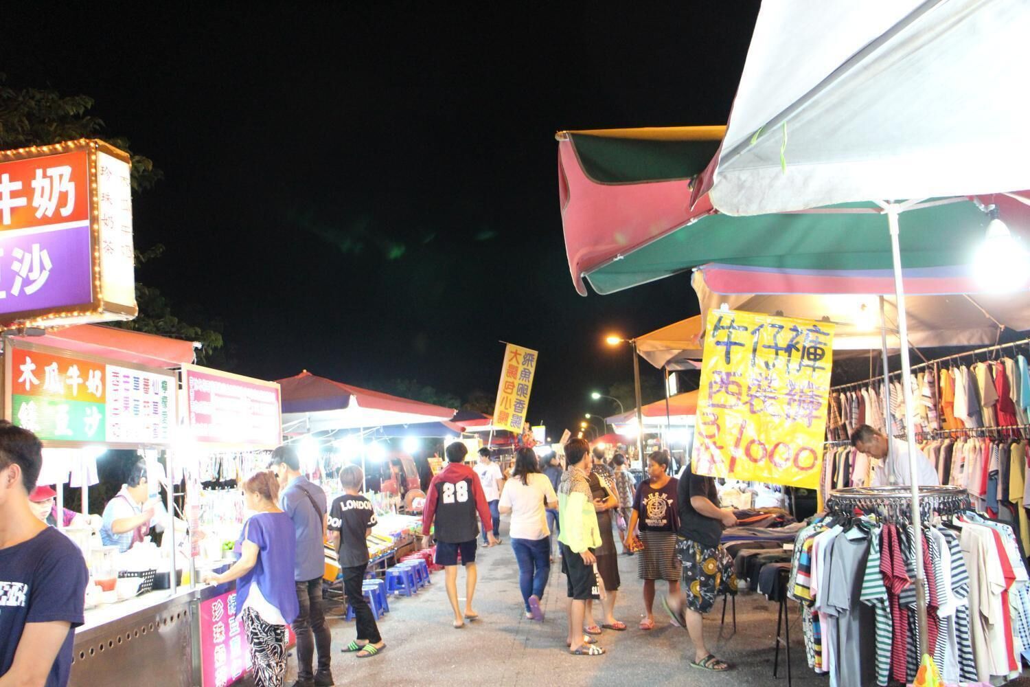 A crowded outdoor market with various stalls and people.