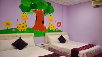 A room with two beds, a mural of giraffes and a tree, and a purple wall.