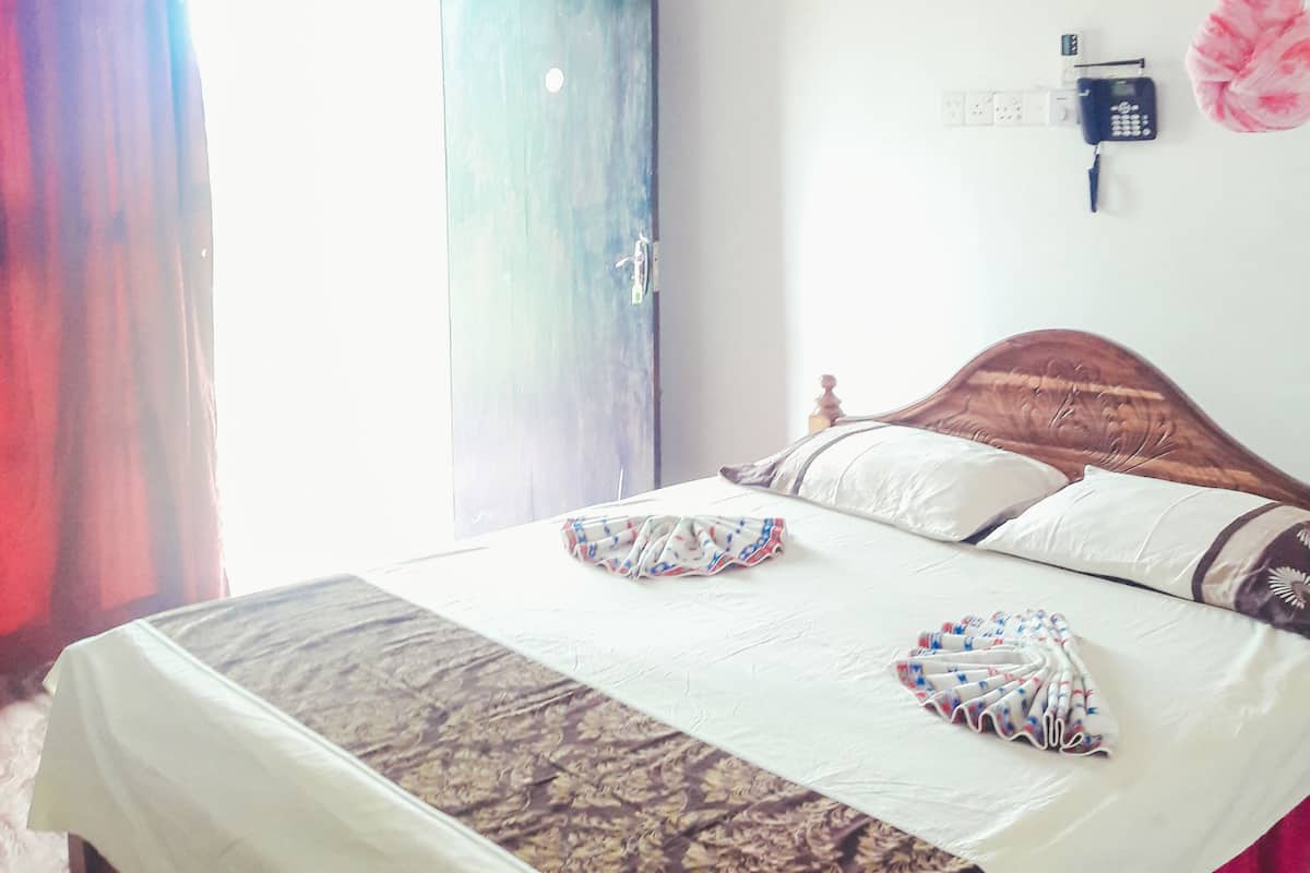 A bedroom with a bed, curtains, a television, and a wall-mounted phone.