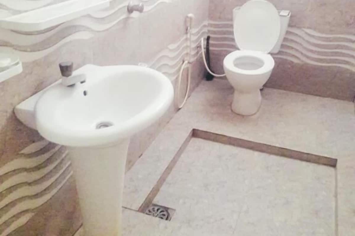 A bathroom with a pedestal sink, toilet, and a wall with a wavy pattern.