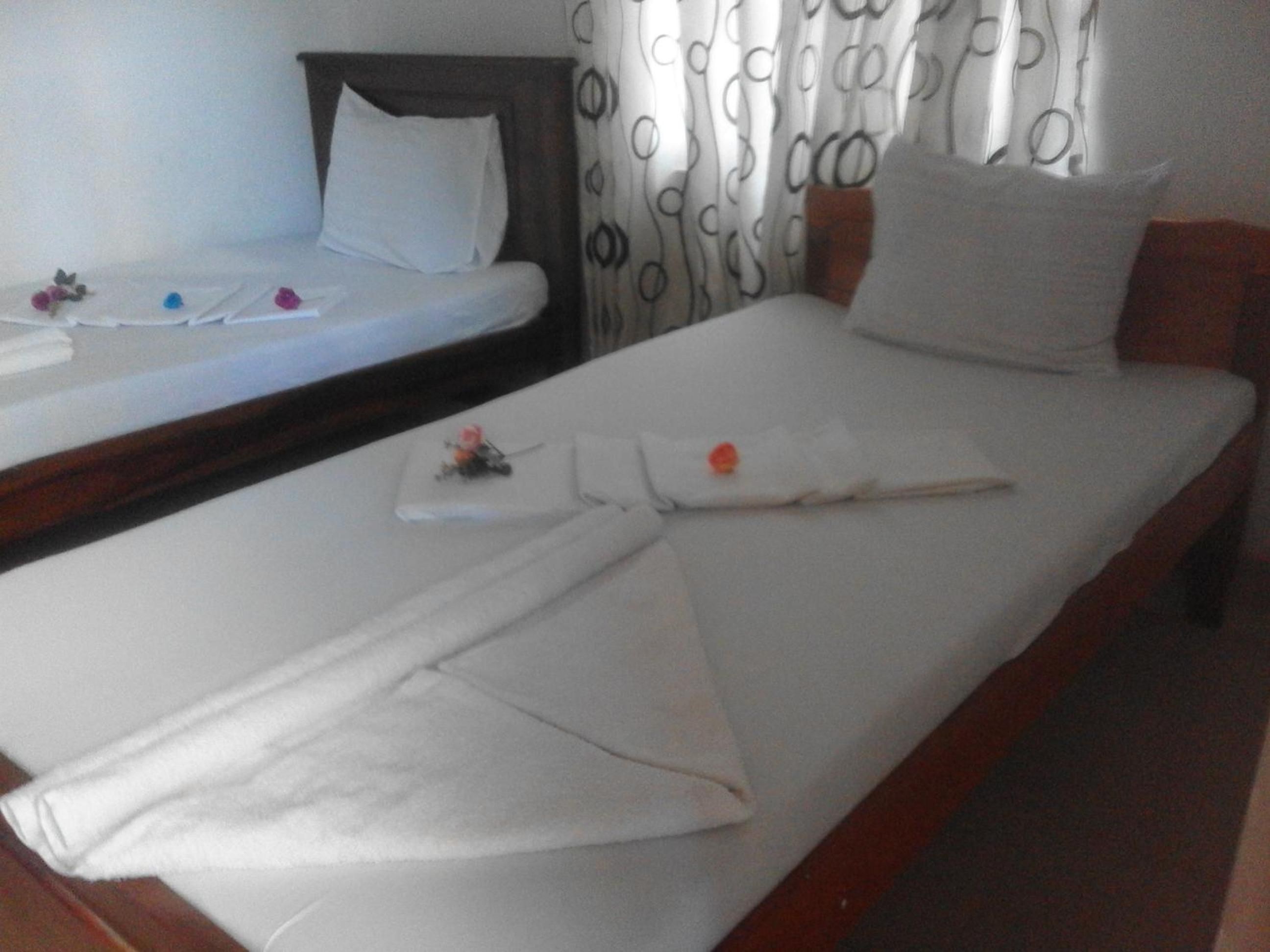 A hotel room with two single beds, a wooden headboard, and a curtain with a circular pattern.
