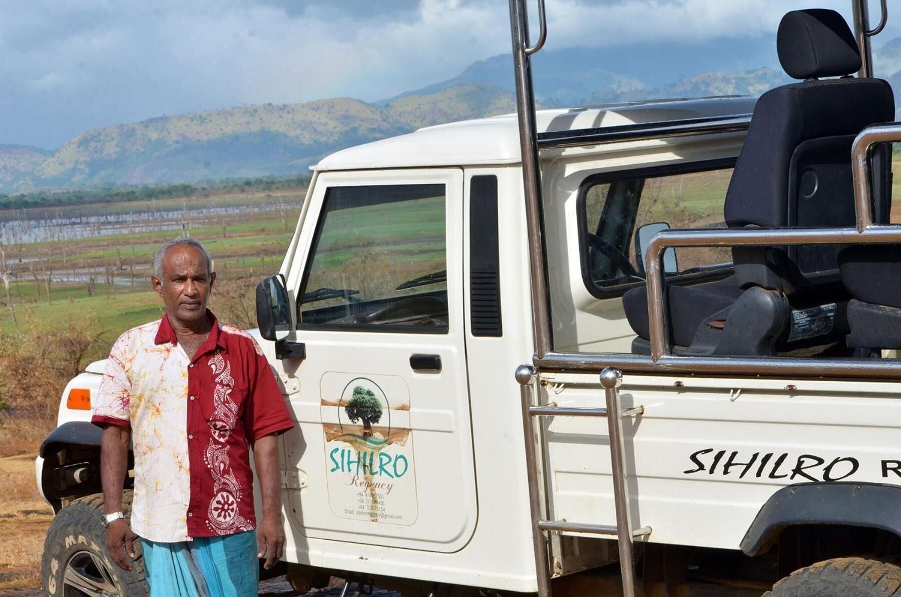 A white vehicle with "SIHILRO" branding and a logo, parked with a person standing beside it.