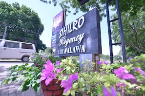 Señal de un hotel llamado 'SIHILRO Regency UDAWAWA' con un vehículo pasando al fondo.