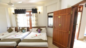 A hotel room with two single beds, a wooden wardrobe, a ceiling fan, and a window with curtains. - Sihilro Regency (Udawalawa)