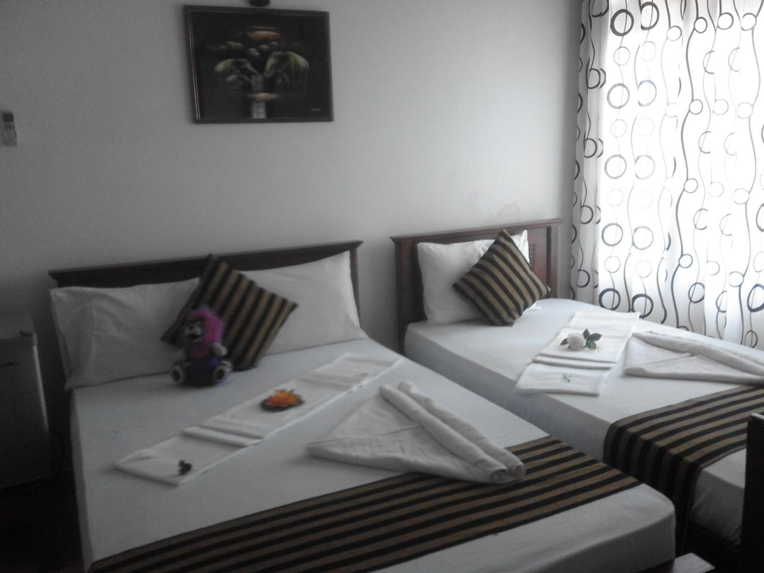 A hotel room with two single beds, each with a pillow and a small decorative item.