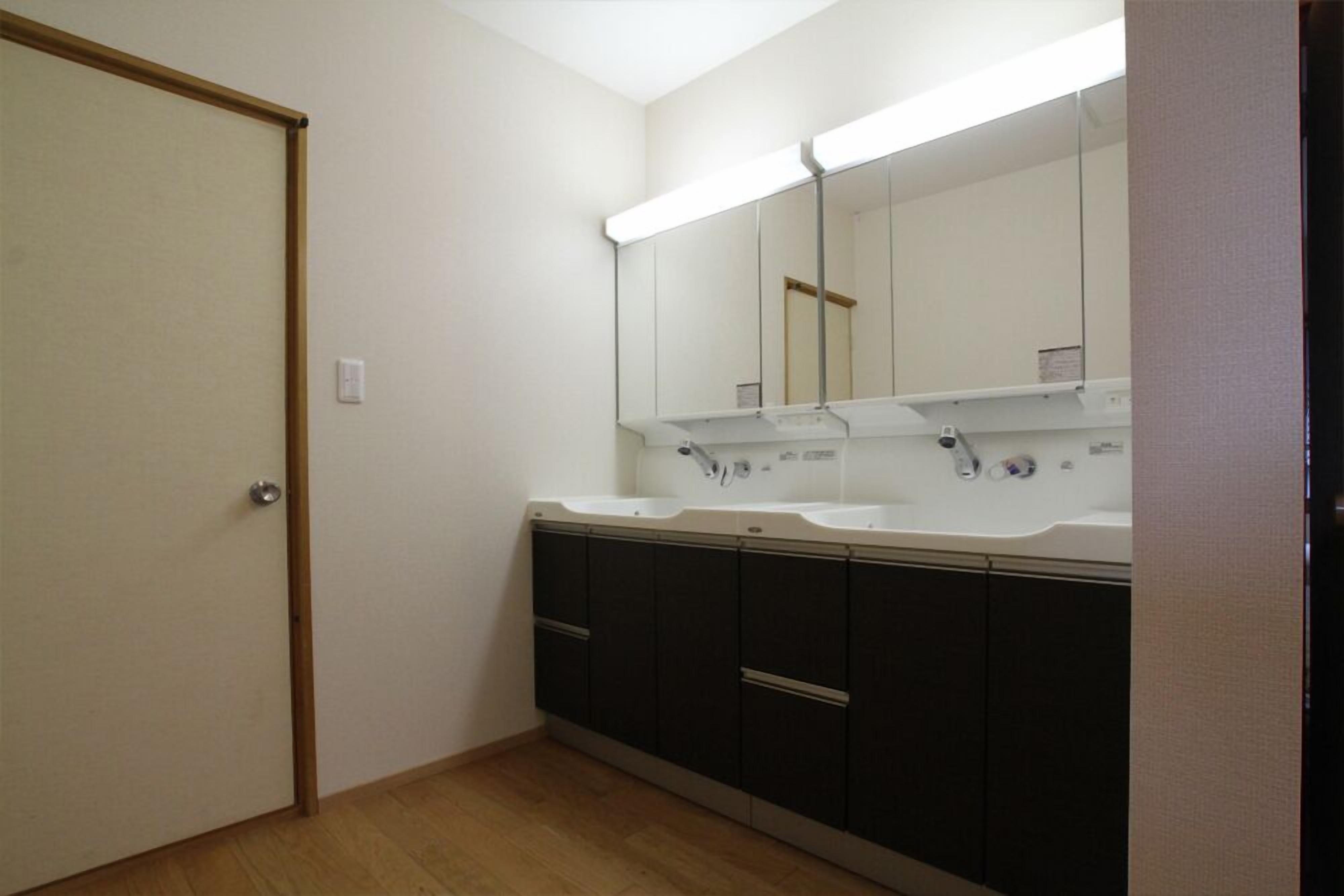 A bathroom with two sinks, dark cabinets, and a mirror above the sinks.