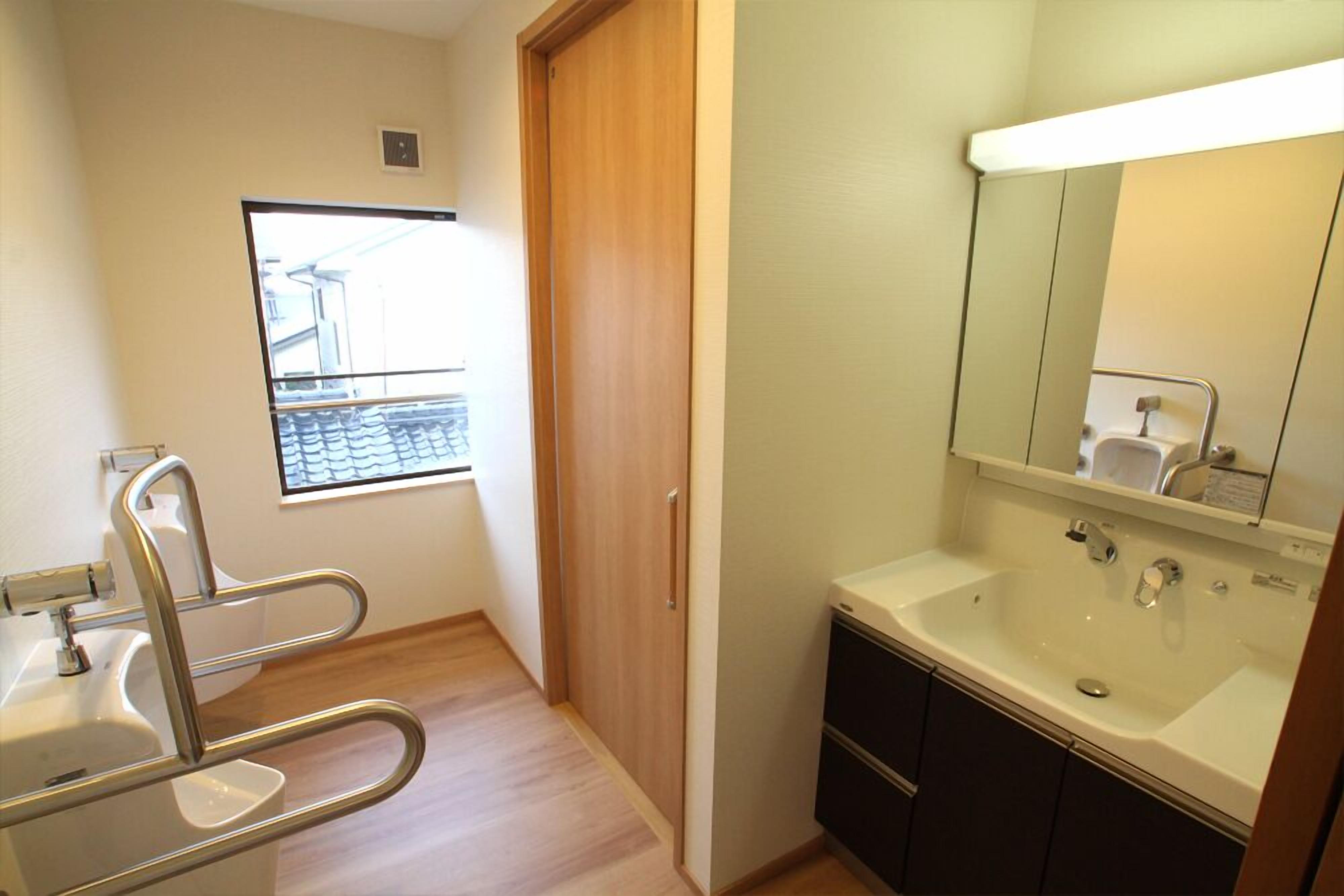 Une salle de bain avec un lavabo, un miroir et une fenêtre donnant sur un immeuble.