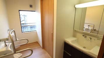 Une salle de bain avec un lavabo, un miroir et une fenêtre donnant sur un immeuble.