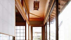 A spacious corridor with wooden flooring and large sliding glass doors leading to an outdoor area. - Yadoya TENKU - Hostel (Asago)