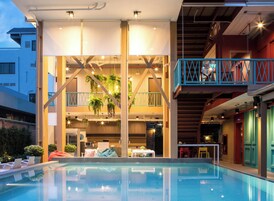 Un hotel moderno con piscina en la azotea, plantas de interior y un comedor.