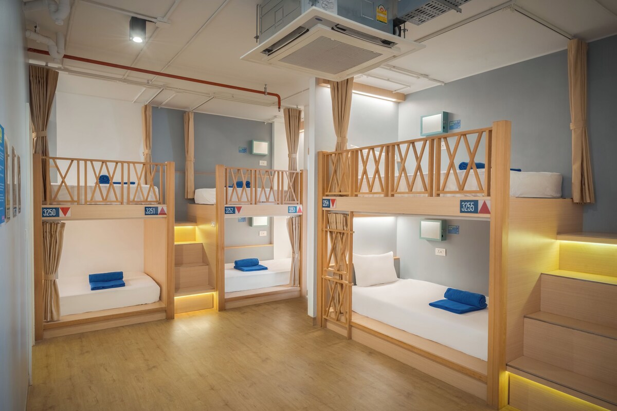 Une chambre d’hôtel avec des lits superposés, chacun étant identifié par un numéro et équipé d’un petit téléviseur.