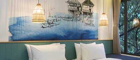 A hotel room with two beds, a large wall mural, and two hanging lamps.