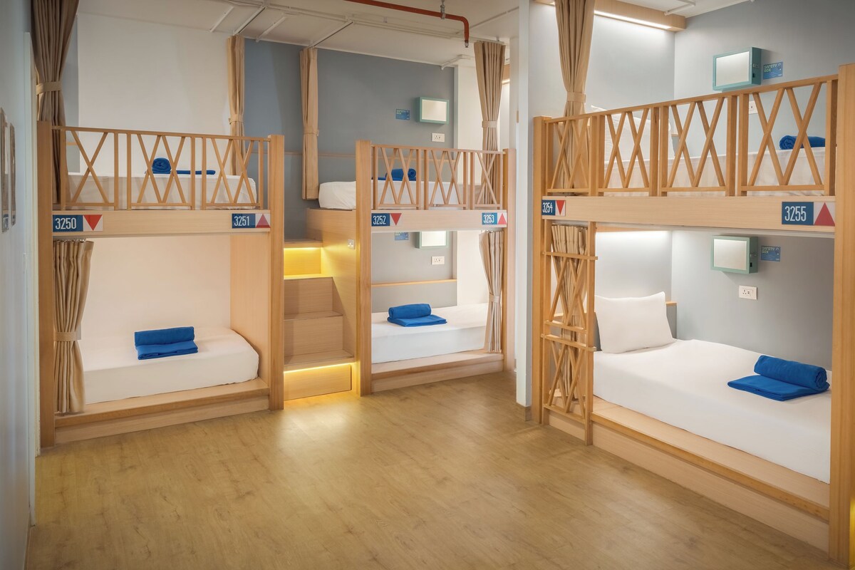 A hotel room with bunk beds, wooden railings, and a small desk with a lamp.