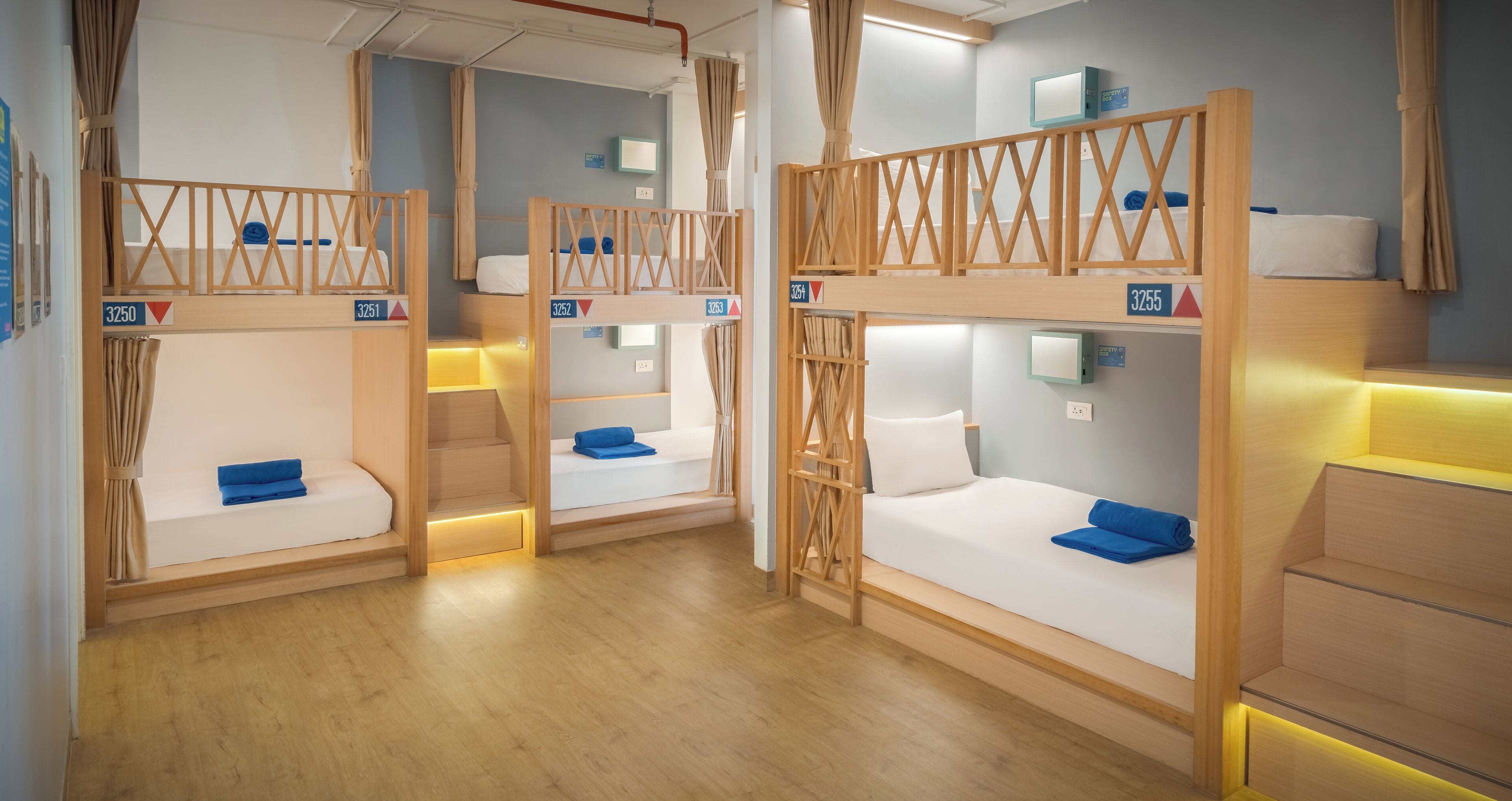 Habitación de hotel con literas, barandillas de madera y un escritorio pequeño con lámpara.