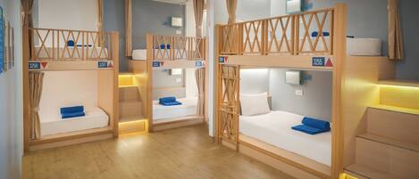 Ein Hotelzimmer mit Etagenbetten, Holzwandverkleidung und einem kleinen Schreibtisch mit Lampe.