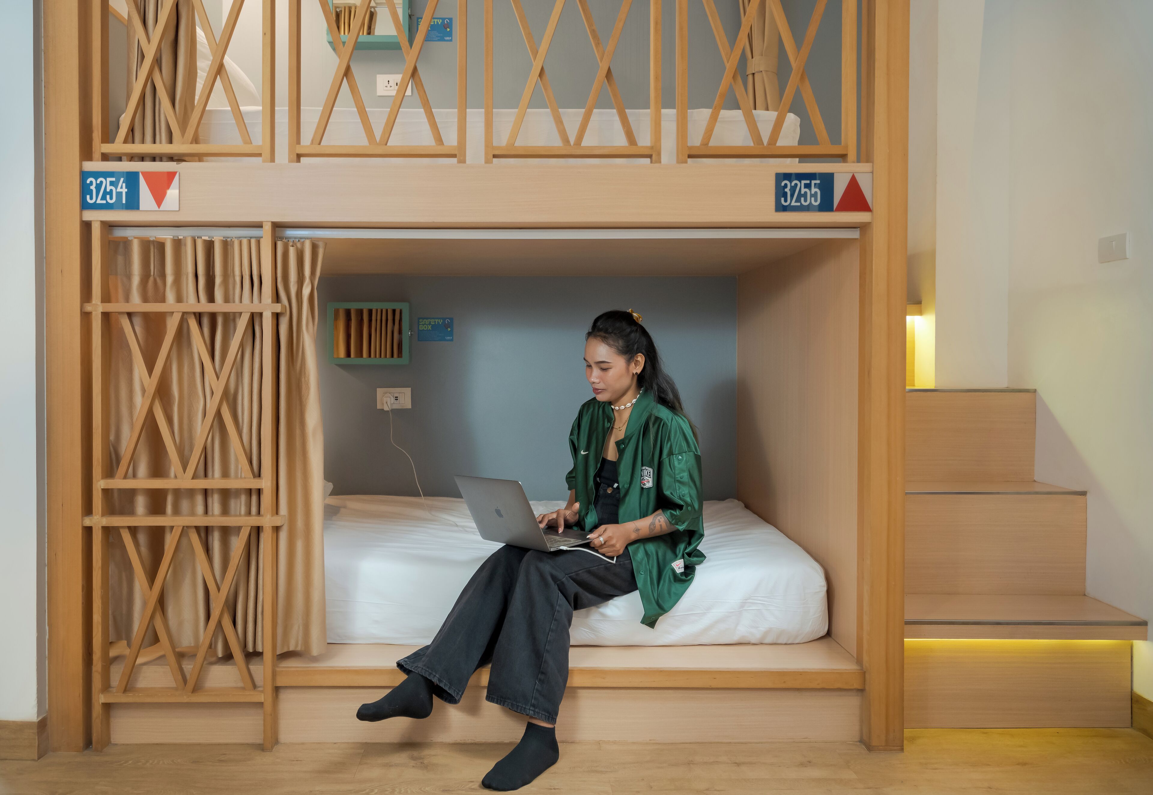 A bunk bed room with a person using a laptop.
