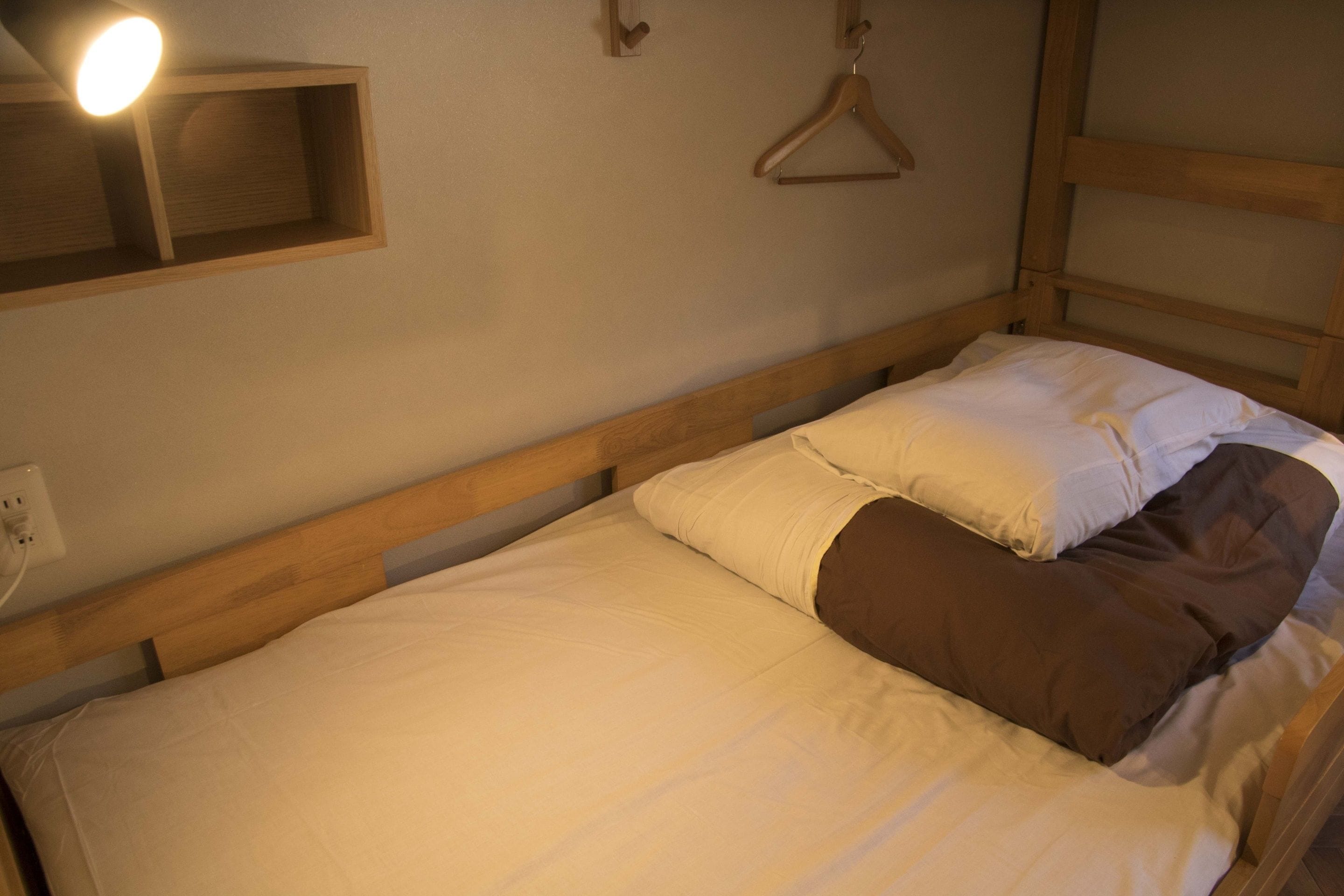 A single bed with a wooden headboard, a bedside table, and a hanging light fixture.
