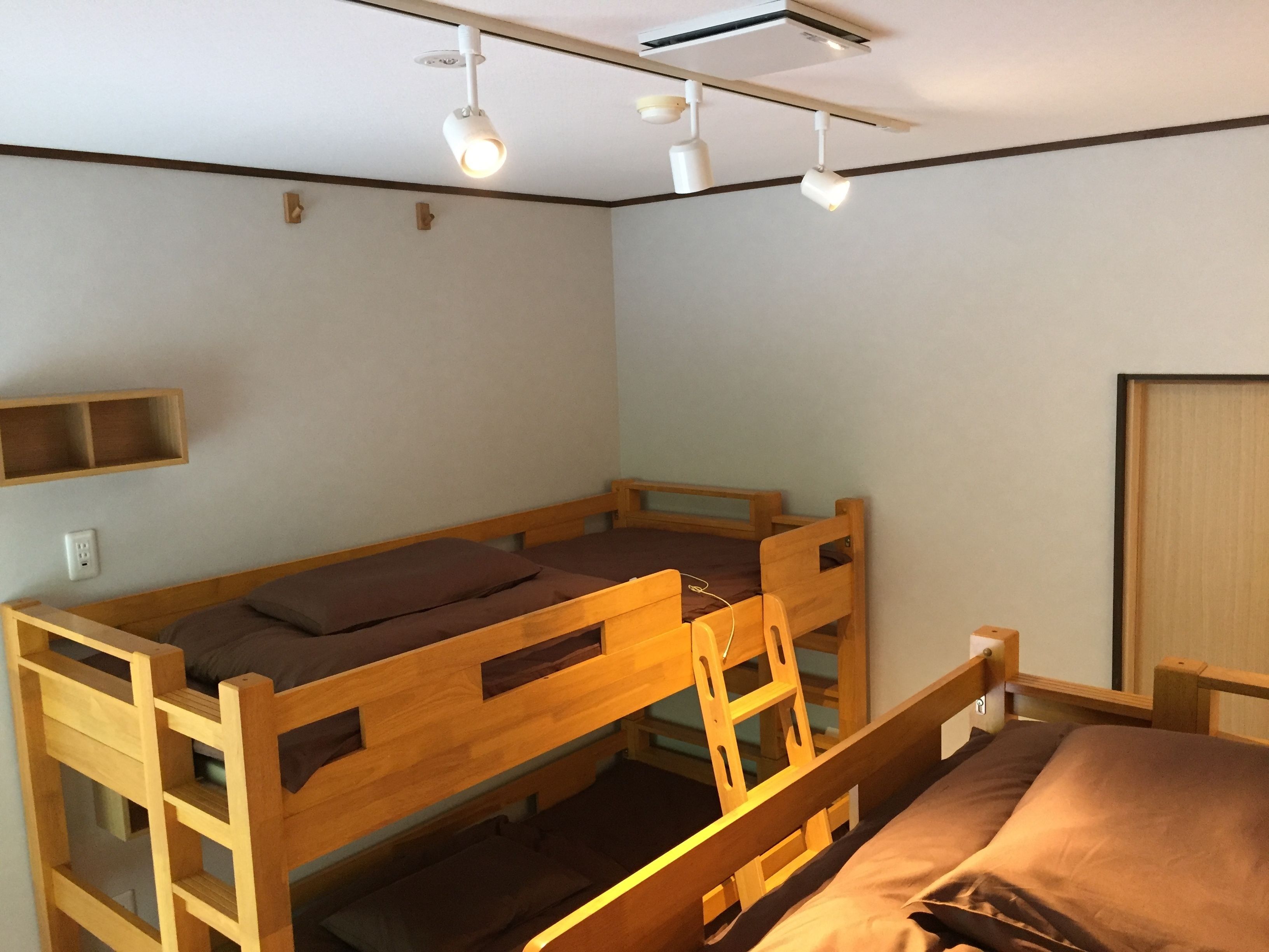 Habitación con literas de madera, repisa sobre la cama y lámpara en el techo.