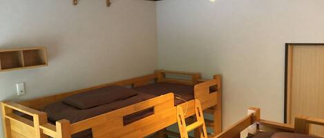 Habitación con literas de madera, repisa sobre la cama y lámpara en el techo.