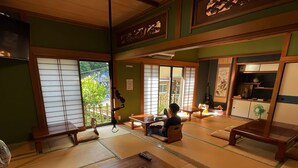 Een traditionele Japanse kamer met tatami vloerbedekking, een lage tafel en een persoon die zit.